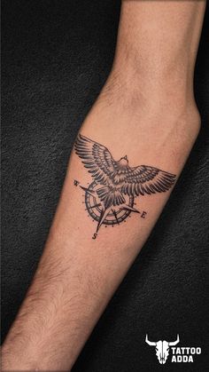 a man's arm with a tattoo on it that has an eagle and compass