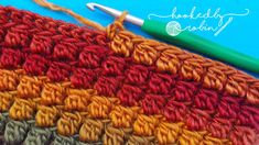 the crochet stitch is being worked on with a green knitting needle next to it