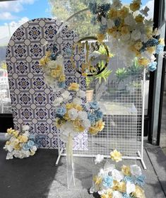 an arrangement of flowers on display in front of a wall with blue and white tiles