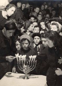 a group of people standing around a table with a lit menorah