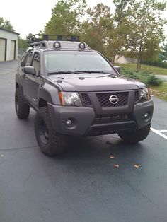 a gray truck parked in a parking lot next to a building with trees behind it