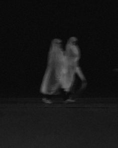 two people are walking in the dark with their arms around each other