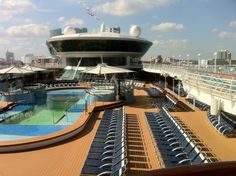 a cruise ship deck with chairs and umbrellas on the top floor, looking out over the pool area