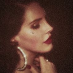 a close up of a person wearing large hoop earrings and piercing on her nose with dark background