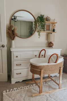 a baby's crib in the corner of a room with a round mirror above it