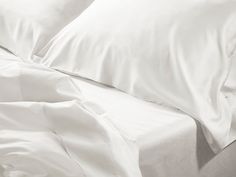 an unmade bed with white sheets and pillows