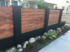 a wooden fence with rocks and succulents on the side