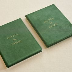 two green books sitting next to each other on top of a white cloth covered table