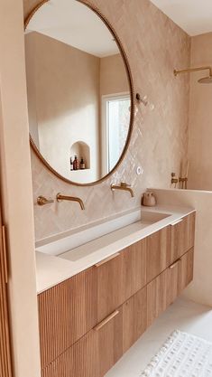 a bathroom with two sinks and a large round mirror