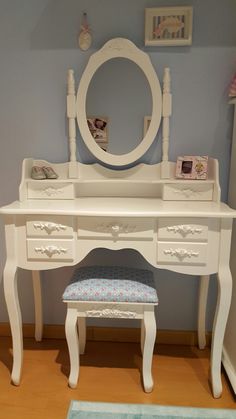 a white dressing table with a mirror and stool