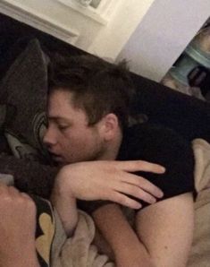 a man laying on top of a bed next to a woman with her arm around him