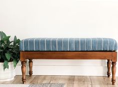 a wooden bench sitting next to a potted plant on top of a hard wood floor