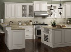 a kitchen with white cabinets and wood floors is pictured in this image, there are two chandeliers hanging from the ceiling