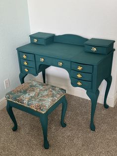 a green desk with two drawers and a foot stool in front of it on carpeted floor