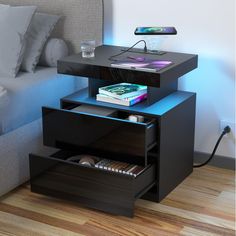 a night stand with two drawers on each side and a phone charging in the middle