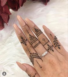 a woman's hand with henna tattoos on it and her wedding ring in the middle