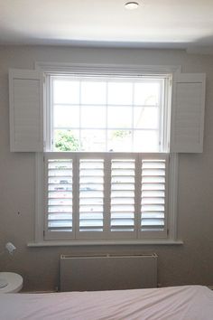 an empty bedroom with white shutters on the window