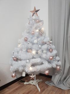 a white christmas tree with pink and silver ornaments