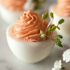 an image of some food that is in the egg shell on the table with flowers