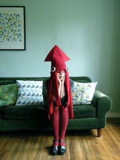 a woman in red is sitting on a couch with her head covered by a blanket