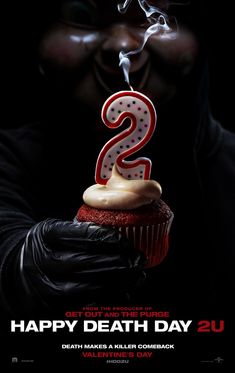 a man holding a cupcake with the number two on it in front of his face