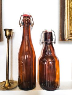 two brown glass bottles sitting on top of a table next to a gold candle holder