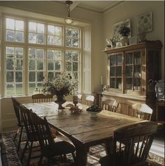 a dining room table and chairs in front of a large window with lots of windows