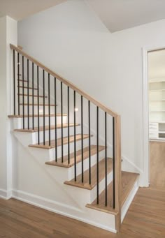 an empty room with stairs and hard wood flooring