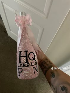 a hand holding a pink bottle with the word hq on it and a bow