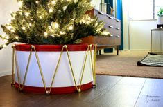 a small christmas tree in a red and white container on the floor next to a rug