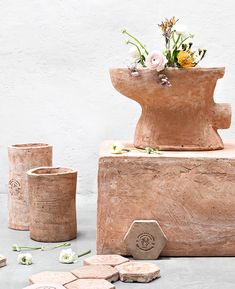 a vase with flowers sitting on top of a wooden block next to other pieces of wood