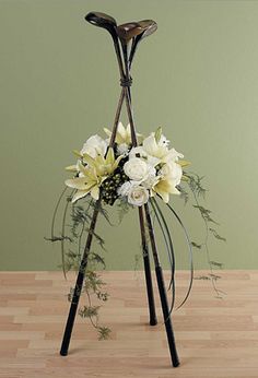 a vase filled with white flowers on top of a wooden floor next to a green wall