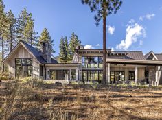 a house in the woods with lots of windows on it's sides and trees around