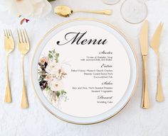 a white and gold plate with flowers on it next to silverware, utensils and napkins