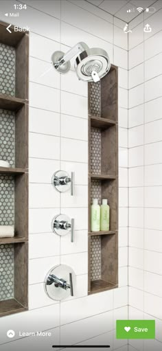 a bathroom with white tile walls and shelves on the wall next to a shower head