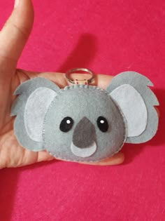 a hand holding a keychain with a koala on it's face