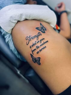 the back of a woman's thigh with butterflies on it, saying strength is what we