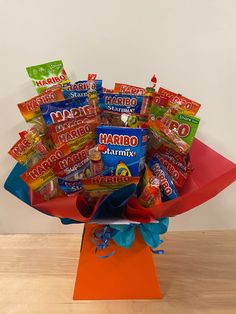 a bouquet of candy and candies sits on top of an orange box with blue ribbon