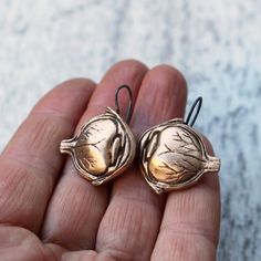 two small metal birds sitting on top of each other's ear hooks in their hand