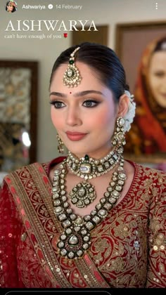 a woman wearing a red and gold outfit with jewelry on her neck, standing in front of