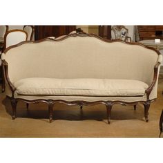 an antique style couch with white linen on it