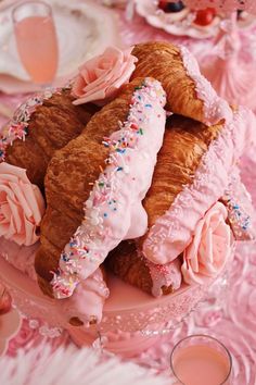 there are croissants with pink frosting and sprinkles on them