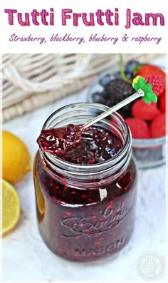 a jar filled with fruit jam next to lemons and raspberries