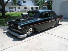 an old black car parked in front of a house with a engine on the hood