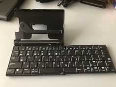 a black keyboard sitting on top of a white table next to a camera and other items