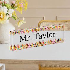 a vase with flowers on a table next to a name plate that says mr taylor