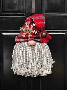 a door hanger with a christmas decoration on it's face and scarf hanging from the front