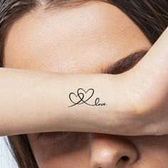 a woman's arm with the word love written on it and a heart tattoo