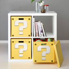 a white shelf with yellow bins and flowers on it, next to a bookcase