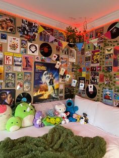 a bed with lots of posters on the wall and stuffed animals sitting on top of it